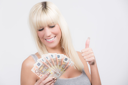 Junge Frau hält lachend in einer Hand Geldscheine